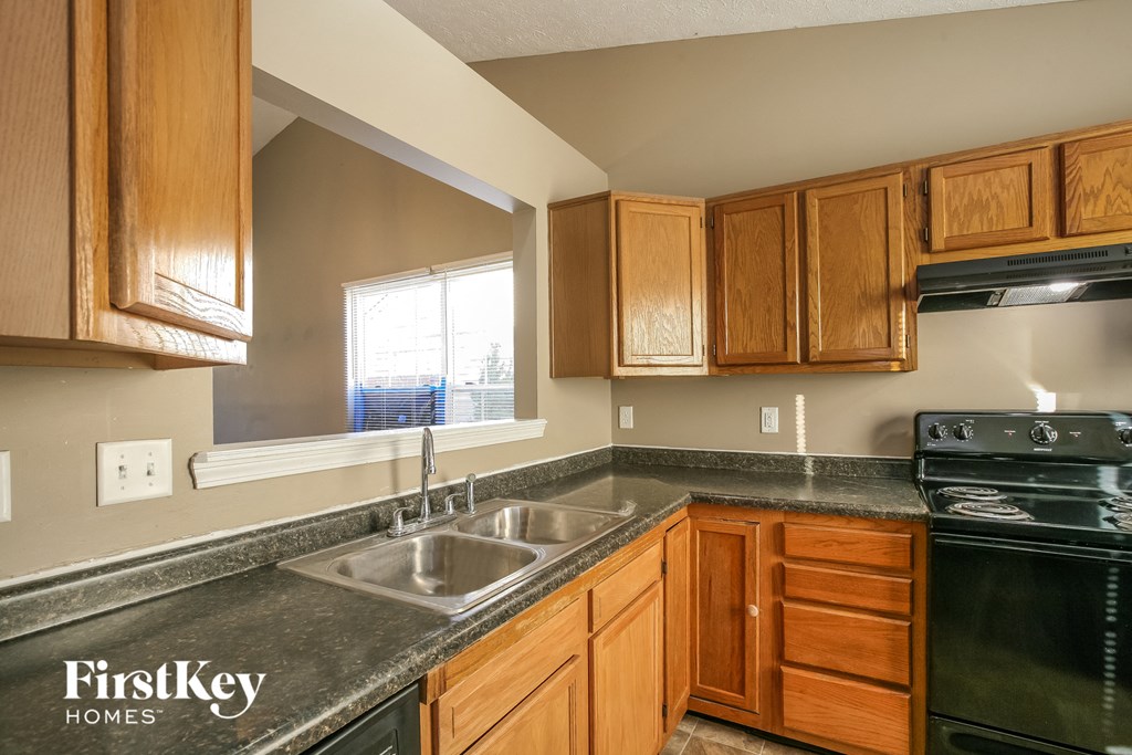 full view of the kitchen with granite countertops and wood cabinets