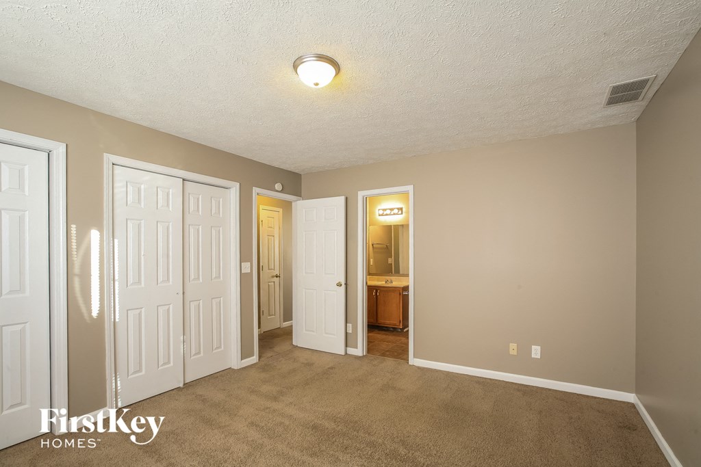 a living room with a carpeted floor and a door to a bathroom