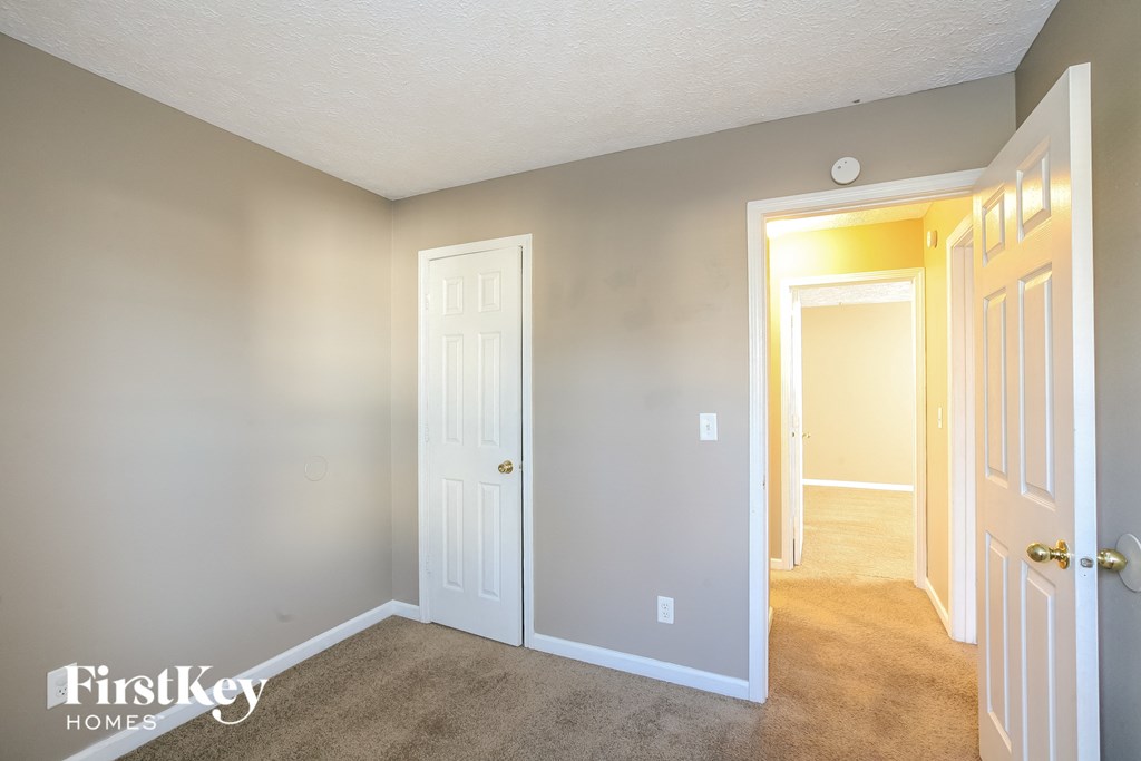 a bedroom with a white door and a hallway to a closet