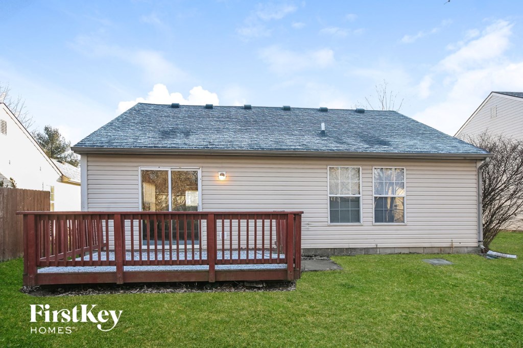 the backyard of a white house with a deck