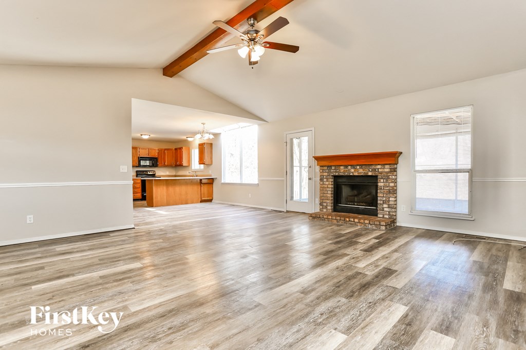 A spacious room with wooden flooring and a fireplace.