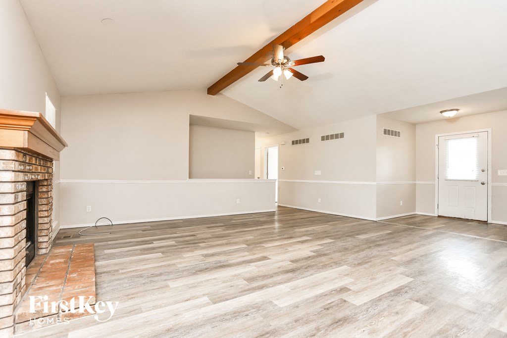 A spacious room with a fireplace and wood flooring.