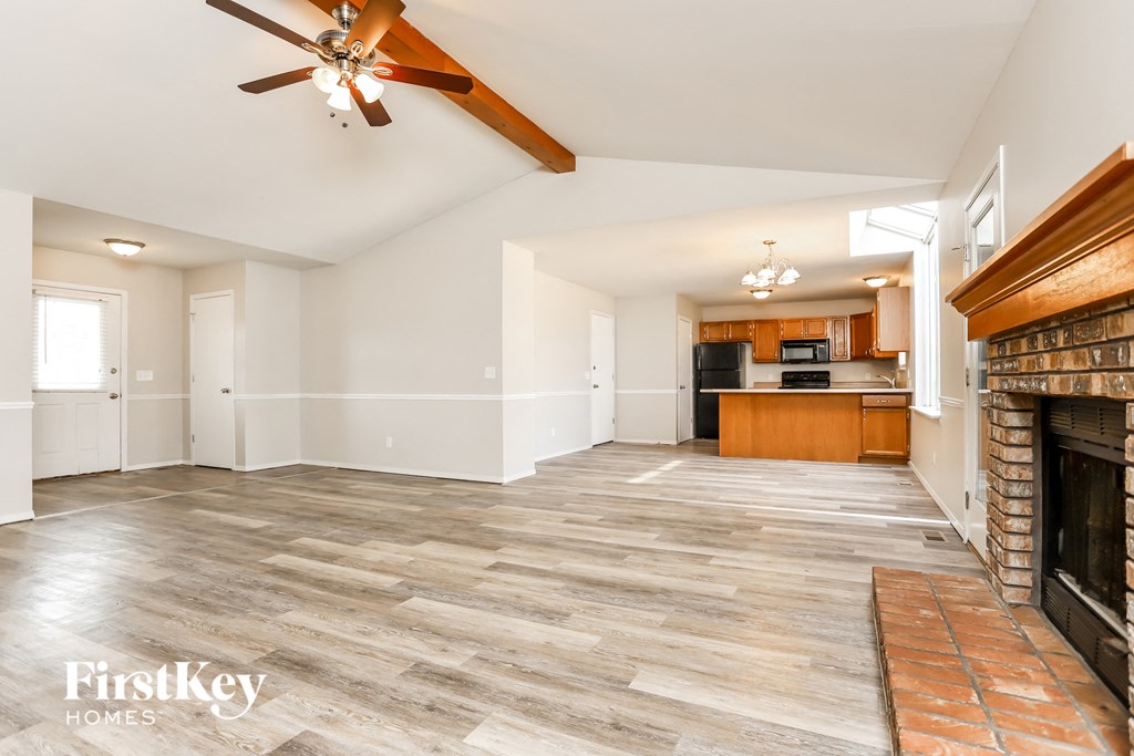 A spacious living room with a fireplace and a ceiling fan.