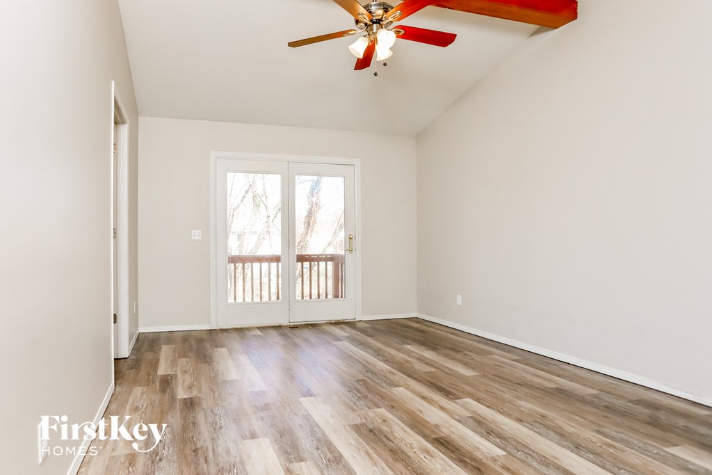 A room with a red ceiling fan and wooden flooring.