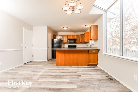 A kitchen with wooden cabinets and a black refrigerator.