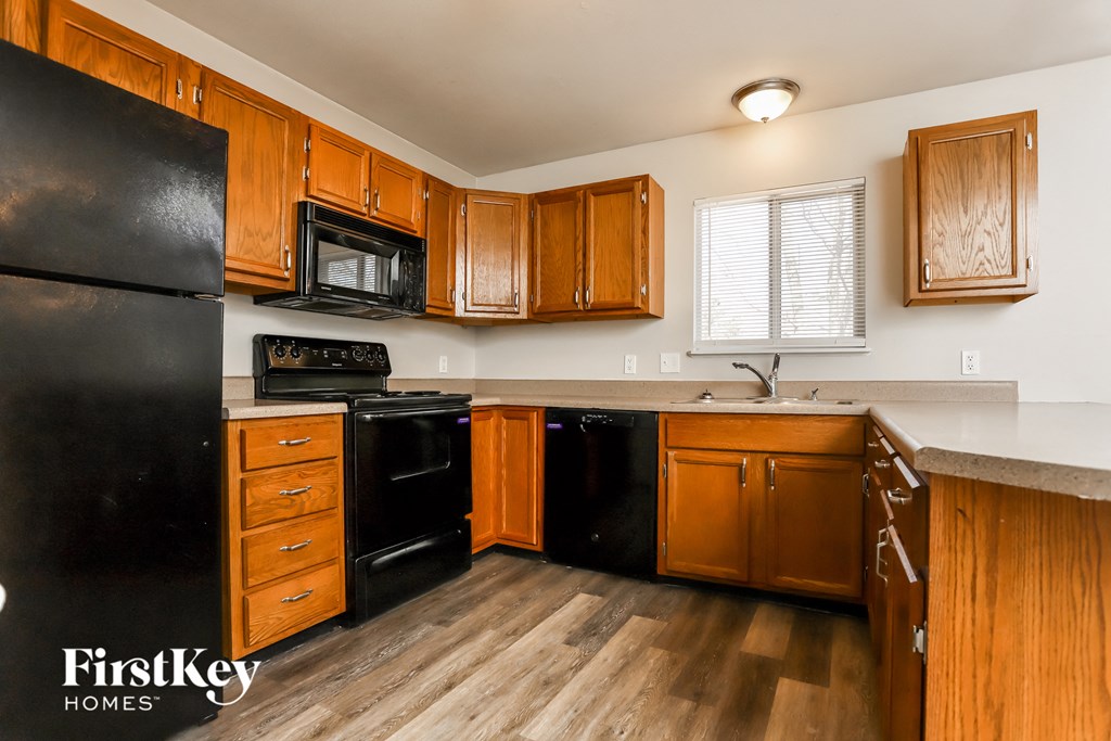 A kitchen with wooden cabinets and black appliances.
