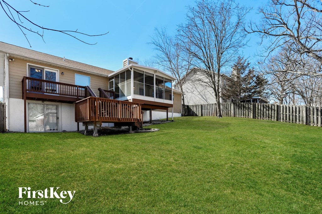 A house with a deck and a fence in the background.