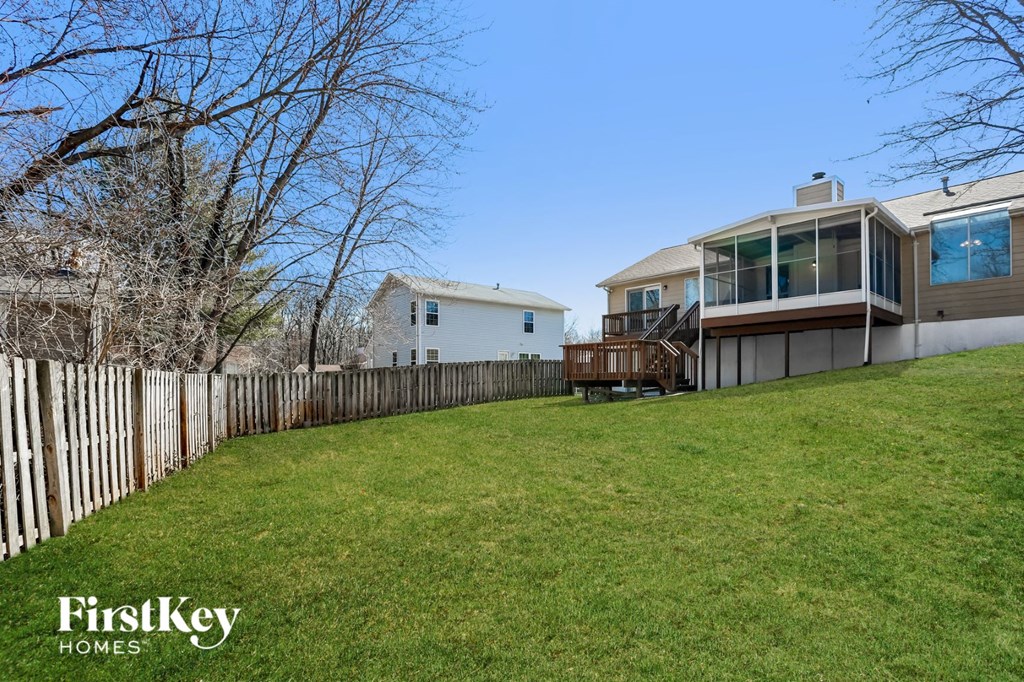 A house with a fence and a tree in the background.