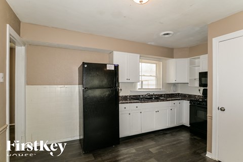 a kitchen with white cabinets and a black refrigerator
