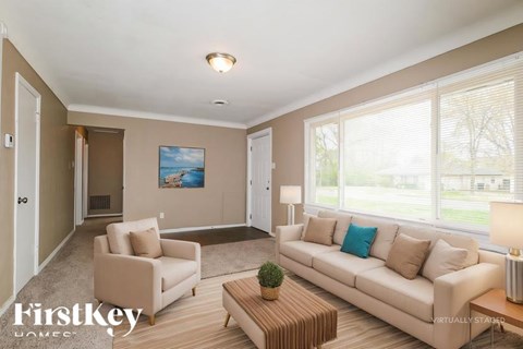 A living room with a couch, chair, and a painting on the wall.