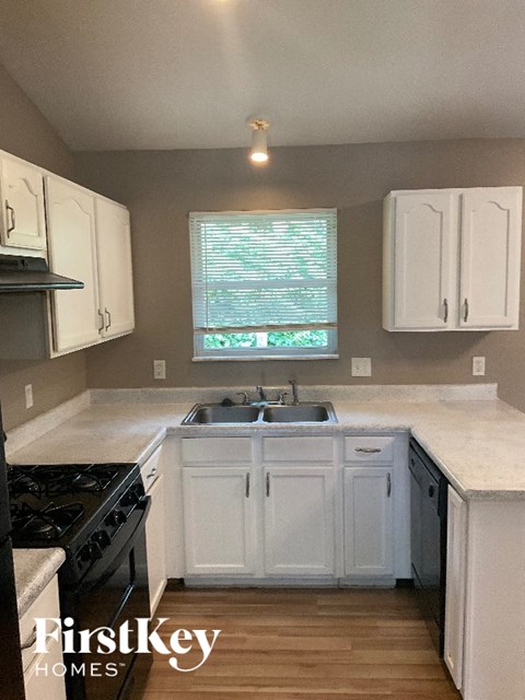 A kitchen with white cabinets and a black stove top oven.