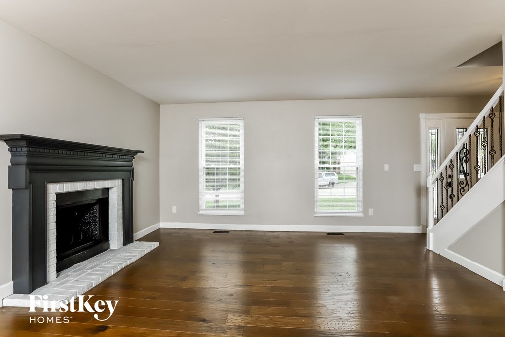 A spacious living room with a fireplace and wooden floors.
