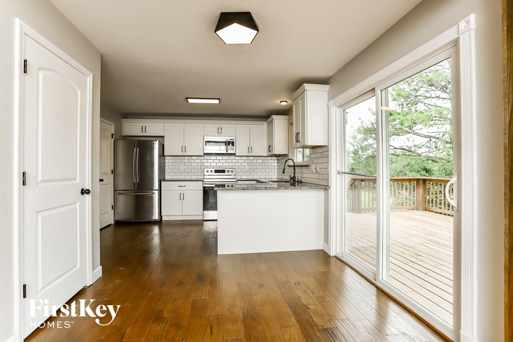 A kitchen with a white countertop and wooden floors.