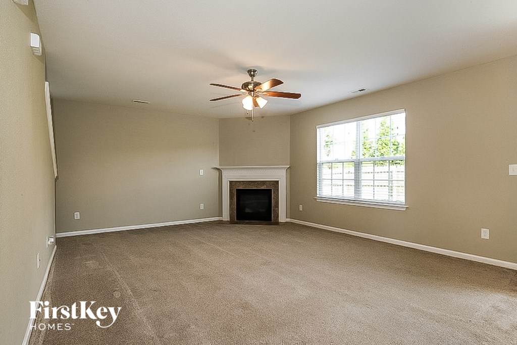 an empty living room with a ceiling fan and a fireplace