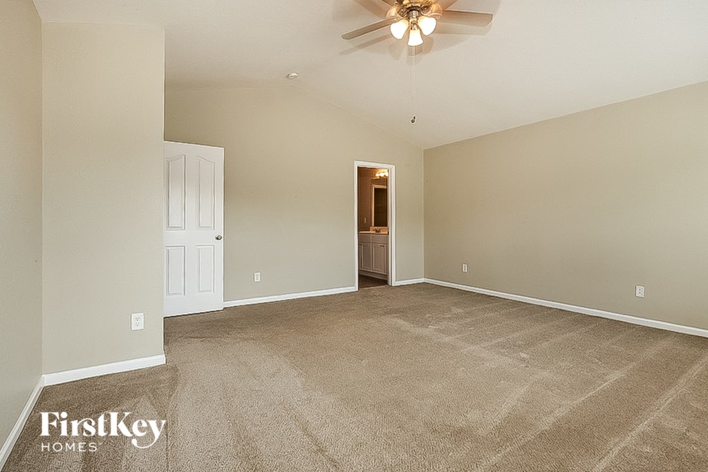 a spacious living room with carpet and a ceiling fan