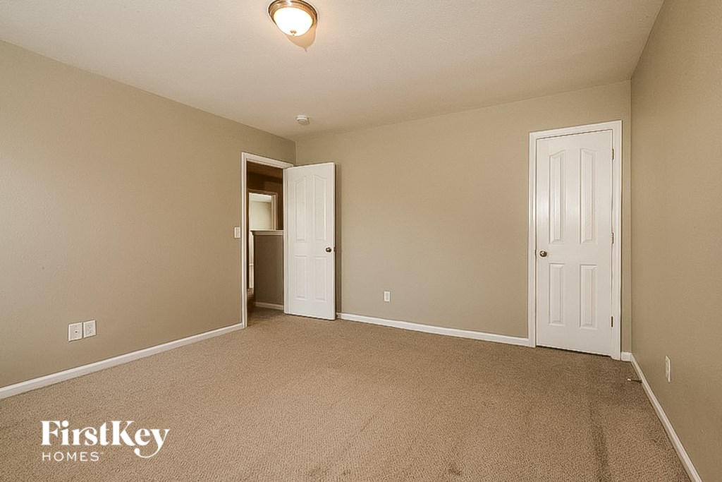 a bedroom with a carpeted floor and a door to a closet