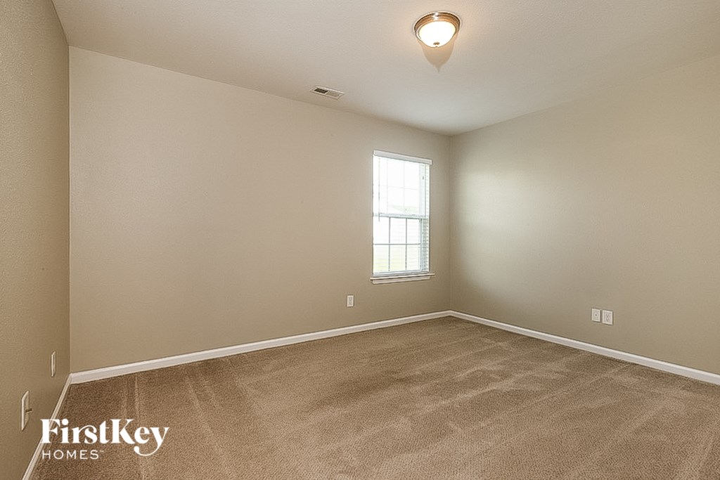 the living room of an empty house with carpet and a window