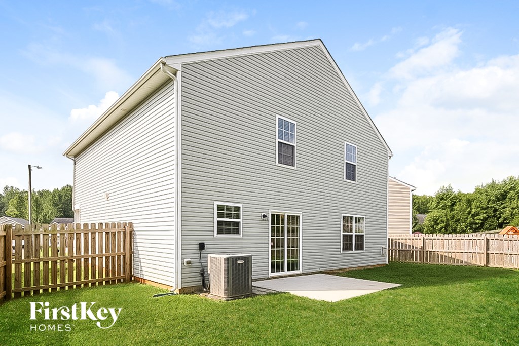 a white house with a fenced in yard and a wooden fence