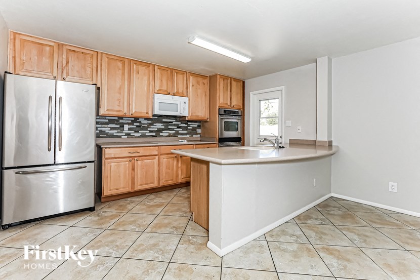 A kitchen with a refrigerator, microwave, oven, and sink.