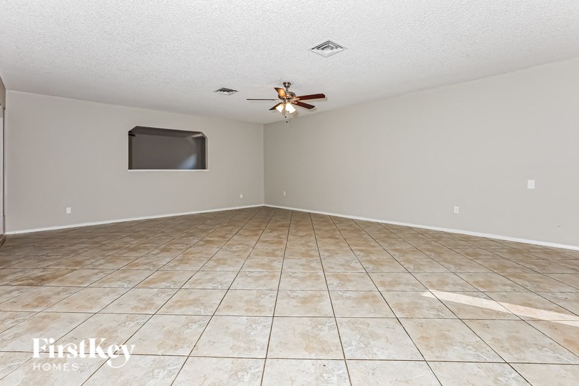 Empty room with a fan and a flat screen TV mounted on the wall.