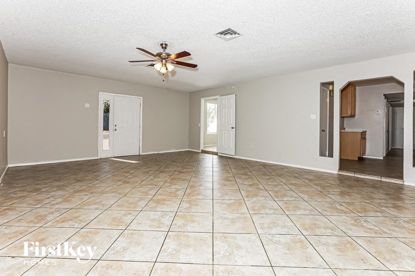 A spacious room with a fan and tile flooring.