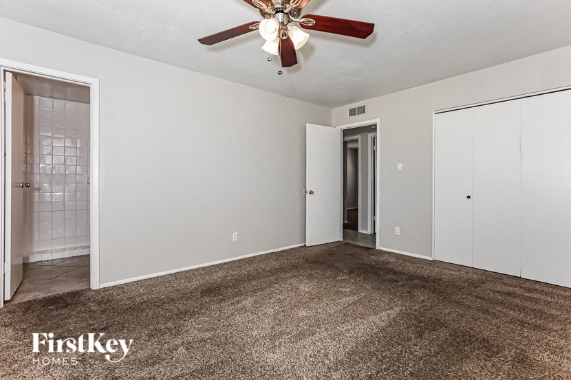 A room with a carpeted floor and a ceiling fan.