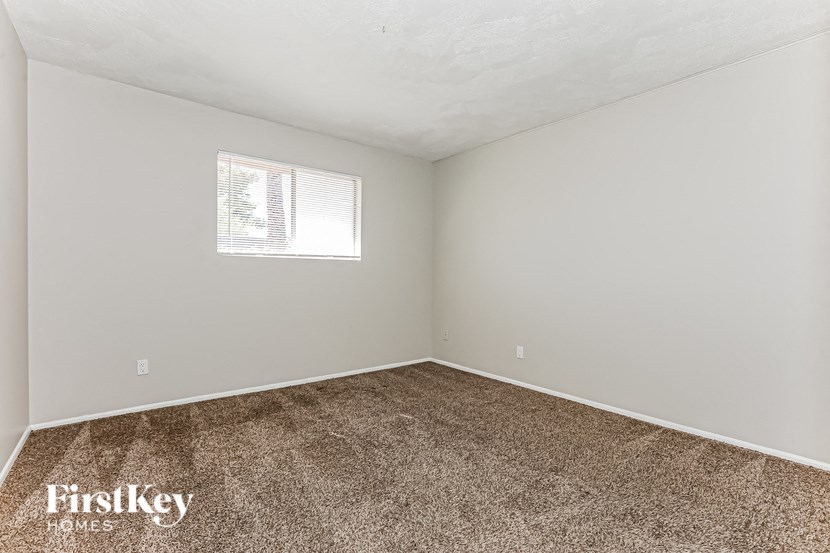 A room with a carpeted floor and a window letting in natural light.