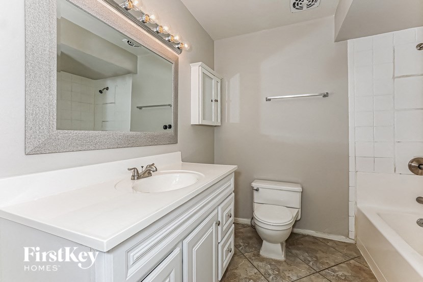 A white bathroom with a mirror, sink, toilet, and bathtub.