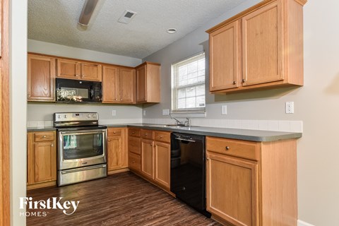 a kitchen with wooden cabinets and a black counter top and a stove and microwave