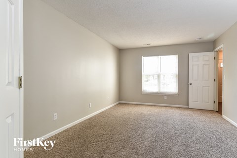 a bedroom with carpet and a white door and window