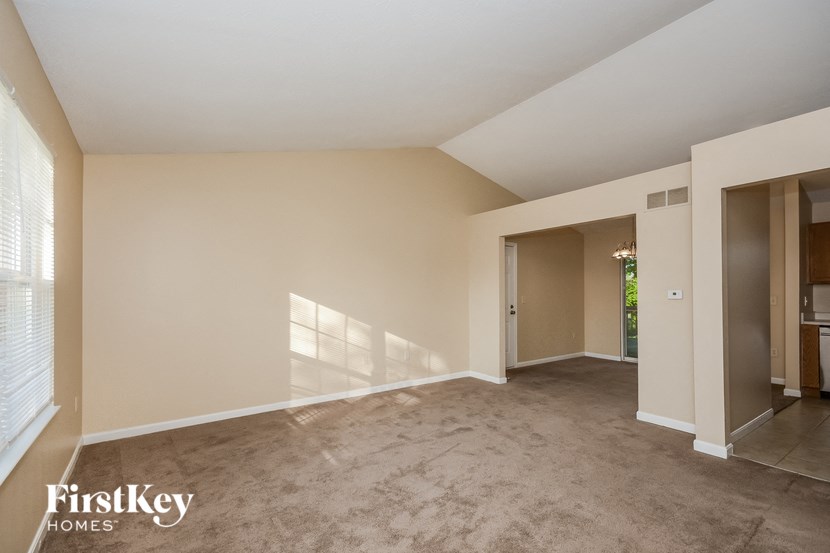a living room with a carpet and a door to a kitchen