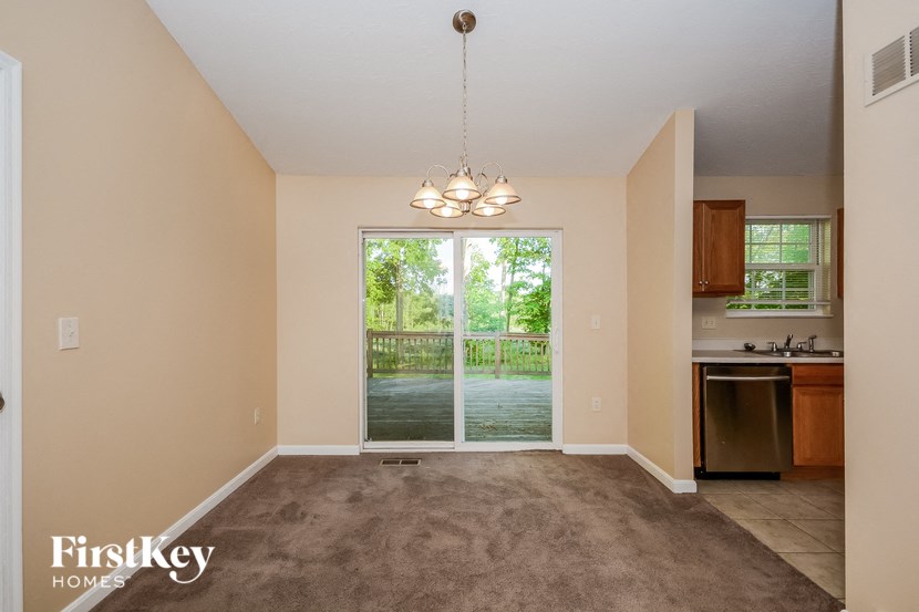 an empty living room with a large window and a kitchen