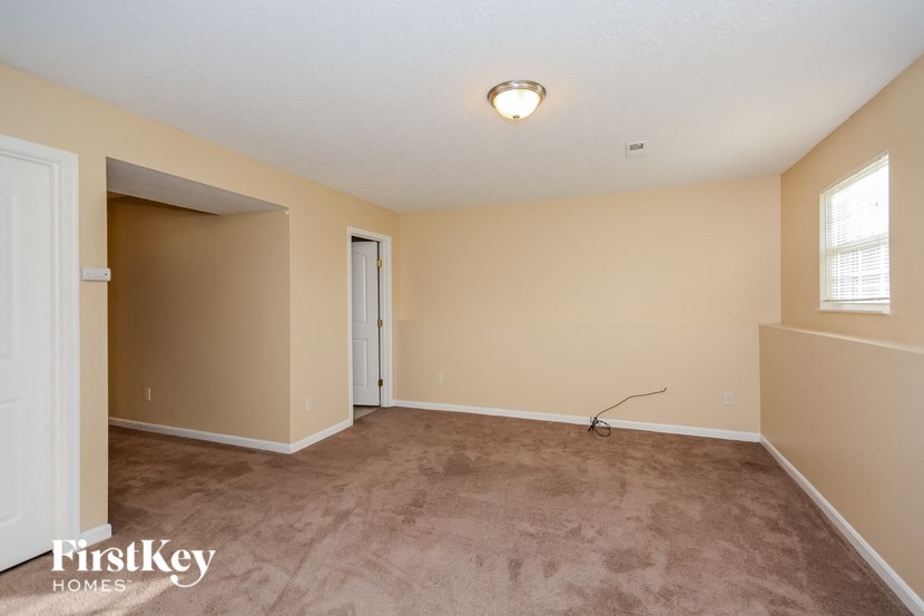the spacious living room with carpeting and a door to the hallway