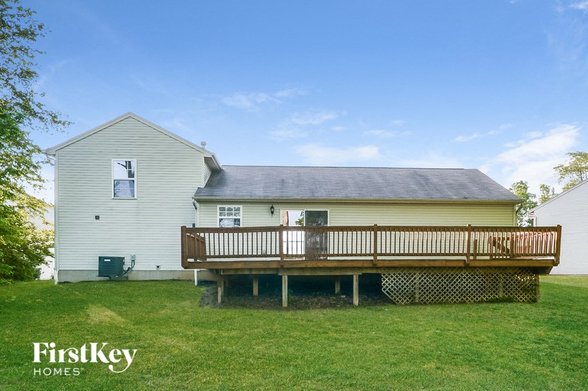 a backyard with a deck and a white house with a gray roof