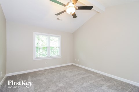 the bedroom of a home with carpet and a ceiling fan