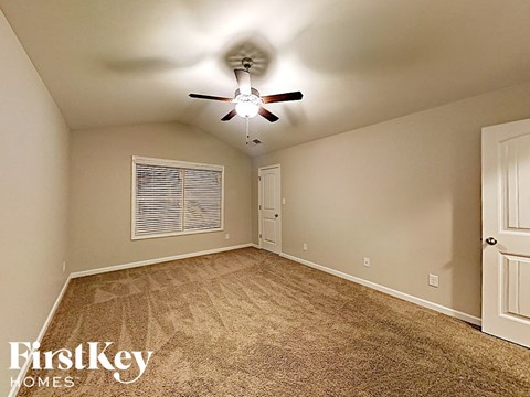 an empty bedroom with a ceiling fan and a window