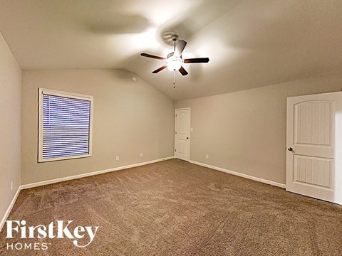 an empty bedroom with a ceiling fan and a door