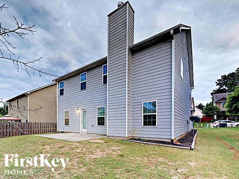 the front of a house with a blue house and a cloudy sky