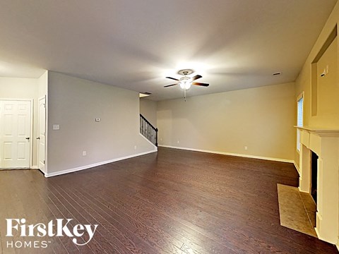 an empty living room with wood flooring and a ceiling fan
