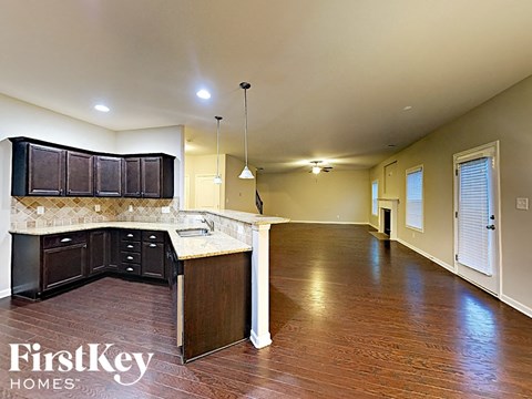 an empty kitchen and living room with wood flooring and white counter tops