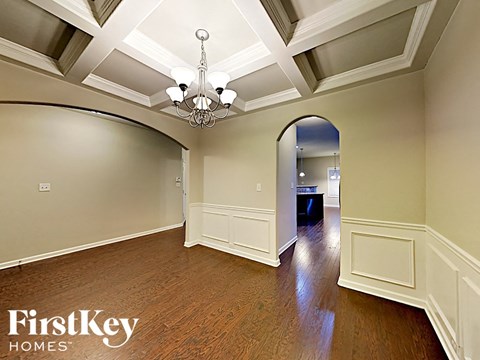 an empty living room with a large archway and a chandelier