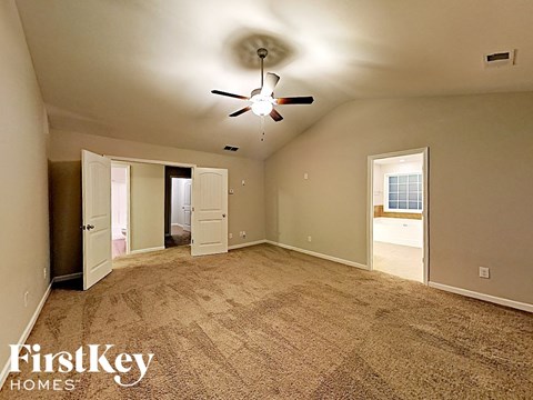 an empty living room with carpet and a ceiling fan