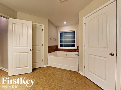a bathroom with a tub and two doors and a window