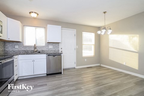 A kitchen with white cabinets and a wooden floor.