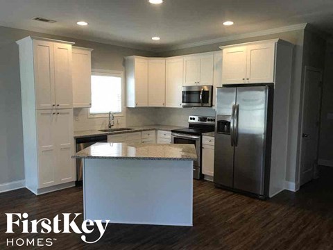 A kitchen with a white island and stainless steel appliances.