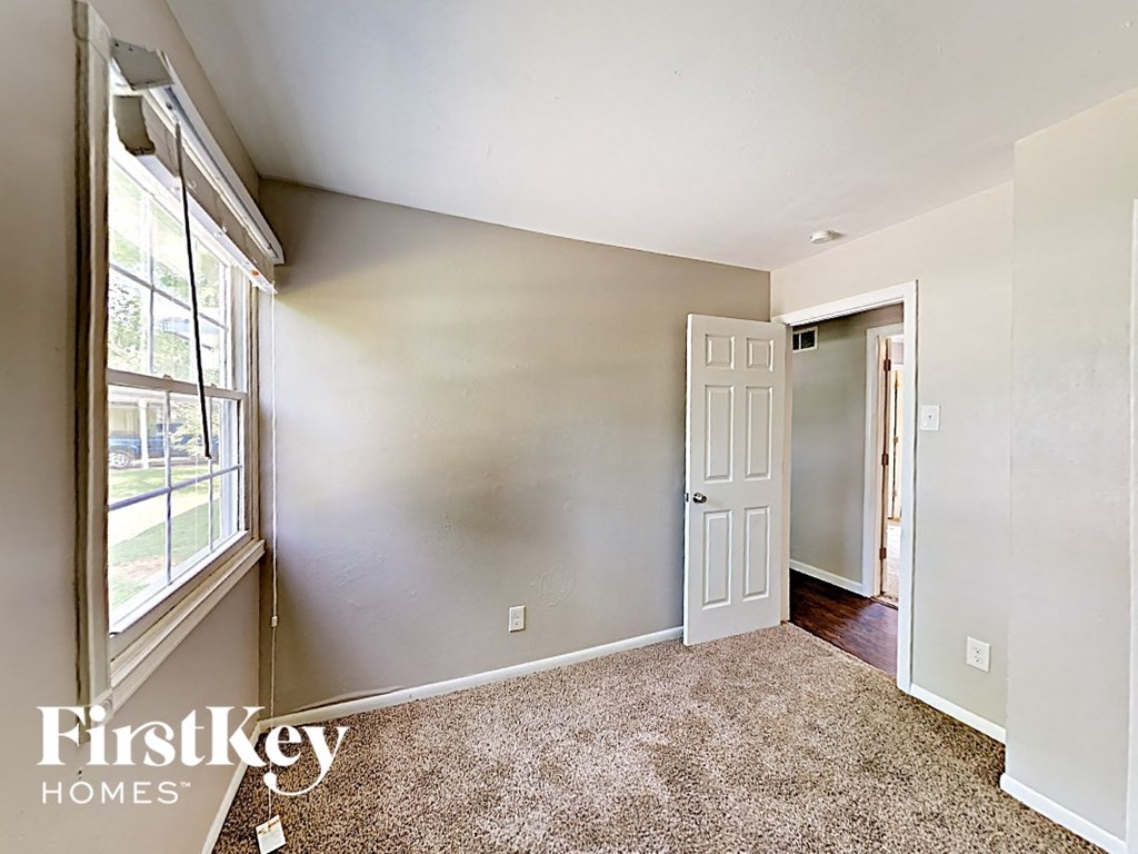 an empty bedroom with a white door and a window