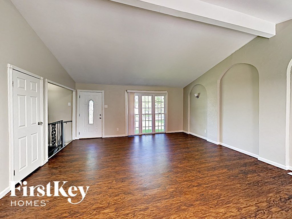 an empty living room with wood floors and white walls