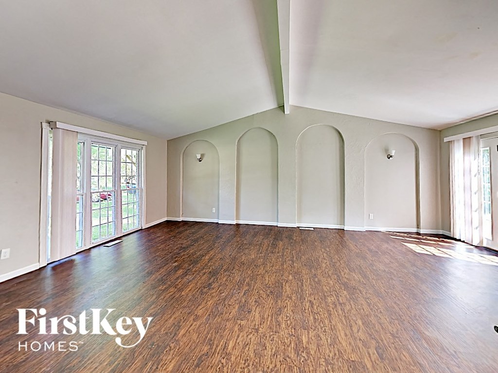 an empty living room with wood floors and white walls