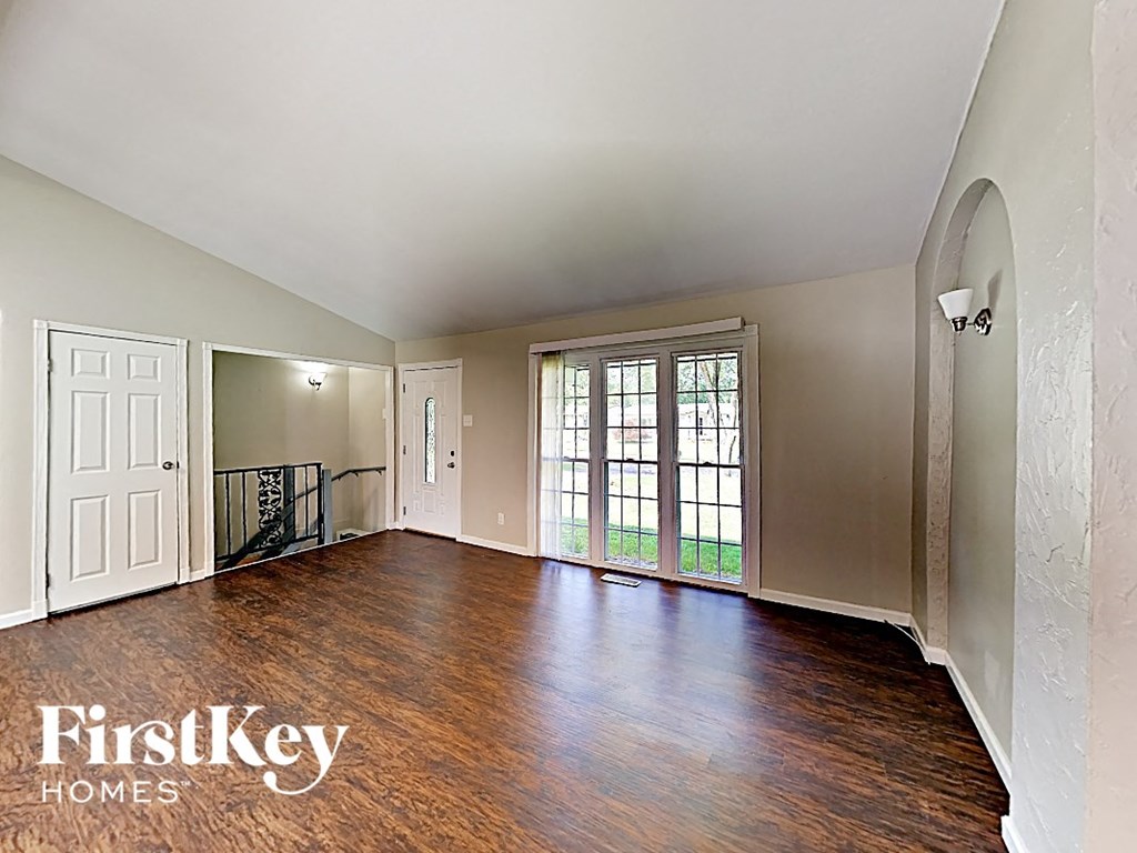 an empty living room with wood flooring and a door to a balcony