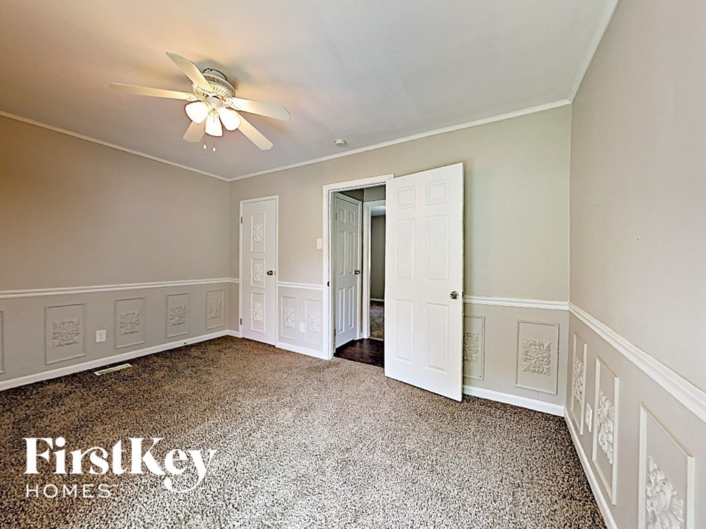 an empty bedroom with white walls and a ceiling fan